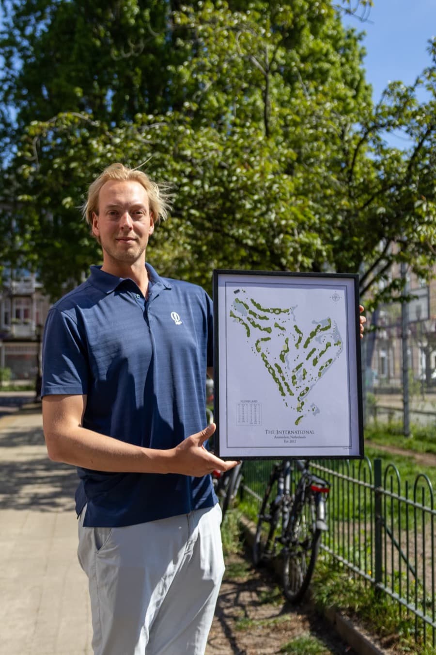 The founder of Course Prints holding a framed print of The International, Amsterdam